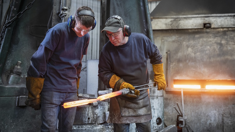 Engineer with apprentice inspecting a forged steel part Engineer with apprentice inspecting a forged steel part